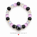 Handmade bracelet with textured black beads, lilac round beads, clear iridescent accents and a black and lilac swirl-effect centre bead