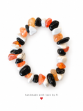 Bracelet with irregular orange, black and white chip-shaped beads, including grey-veined white beads